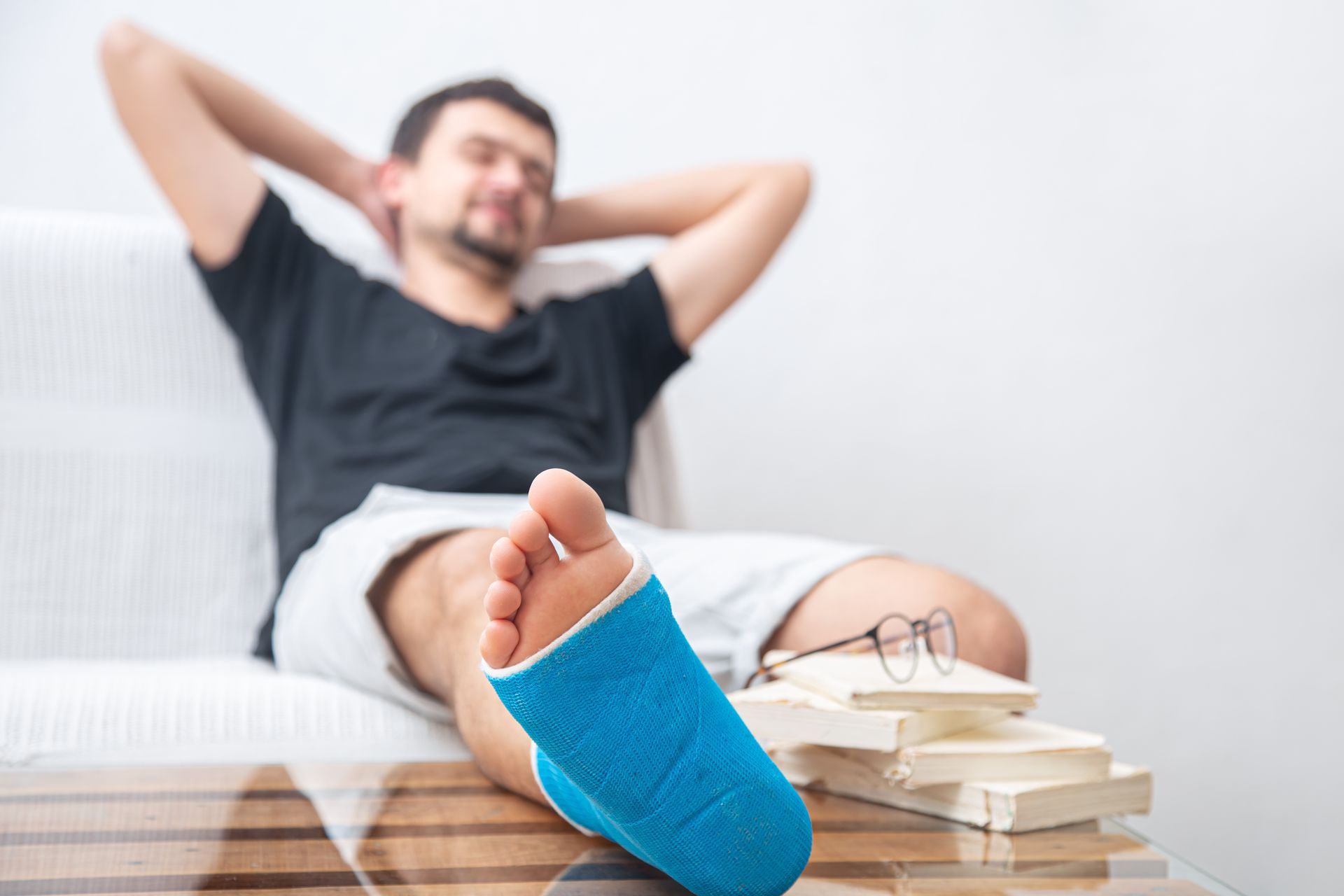 A man with a cast on his foot is sitting on a couch.