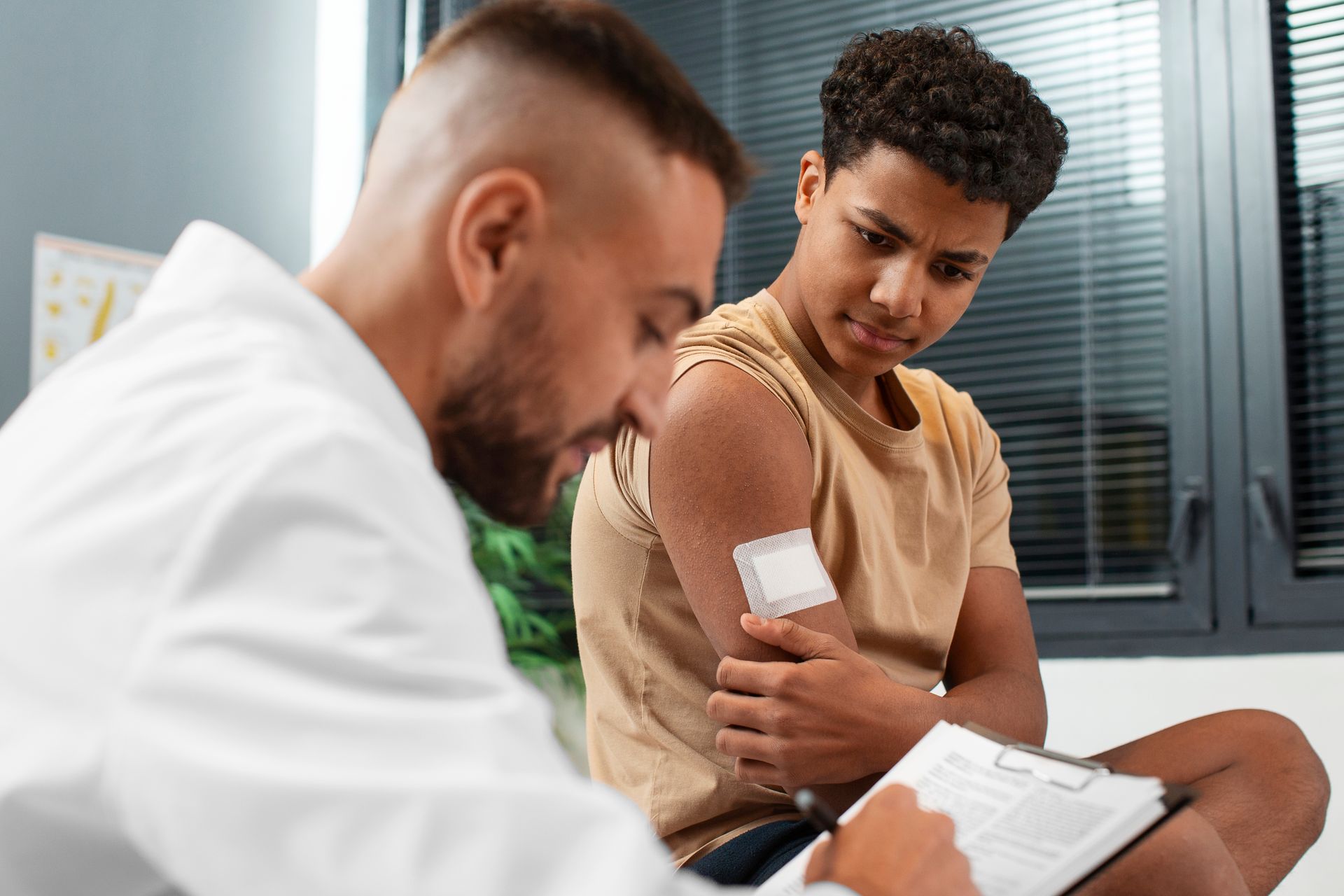 A doctor is talking to a young boy who has a bandage on his arm.