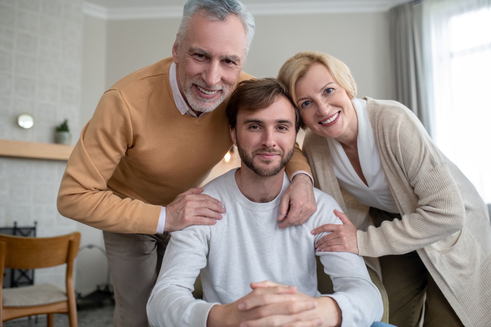 A man in a wheelchair is posing for a picture with his parents.