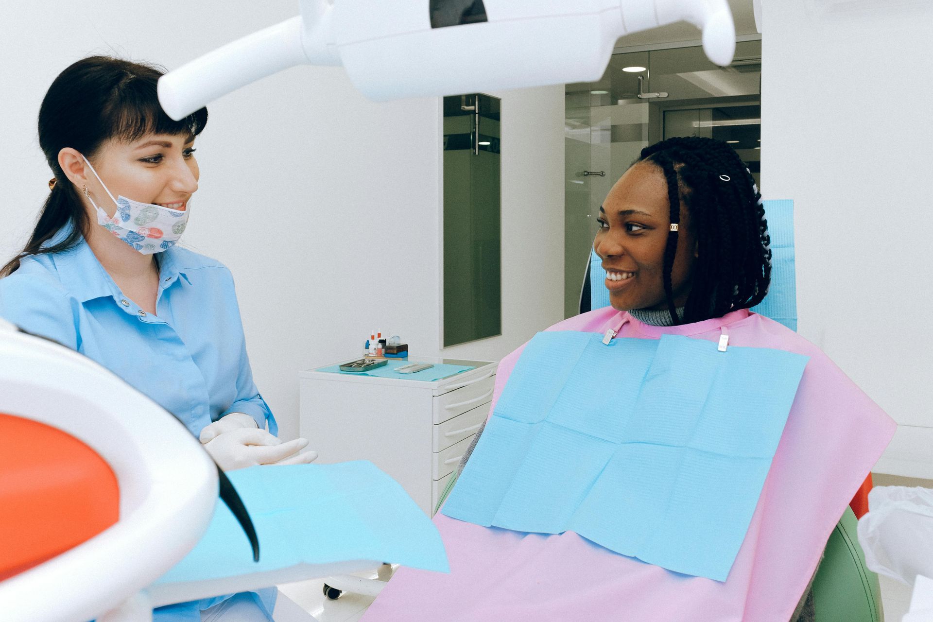 A woman is sitting in a dental chair talking to a dentist.