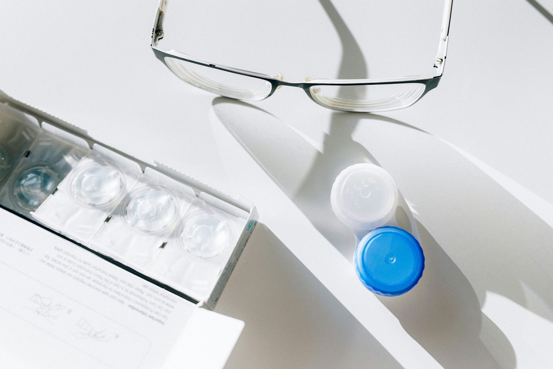 A pair of glasses and a box of contact lenses on a table.