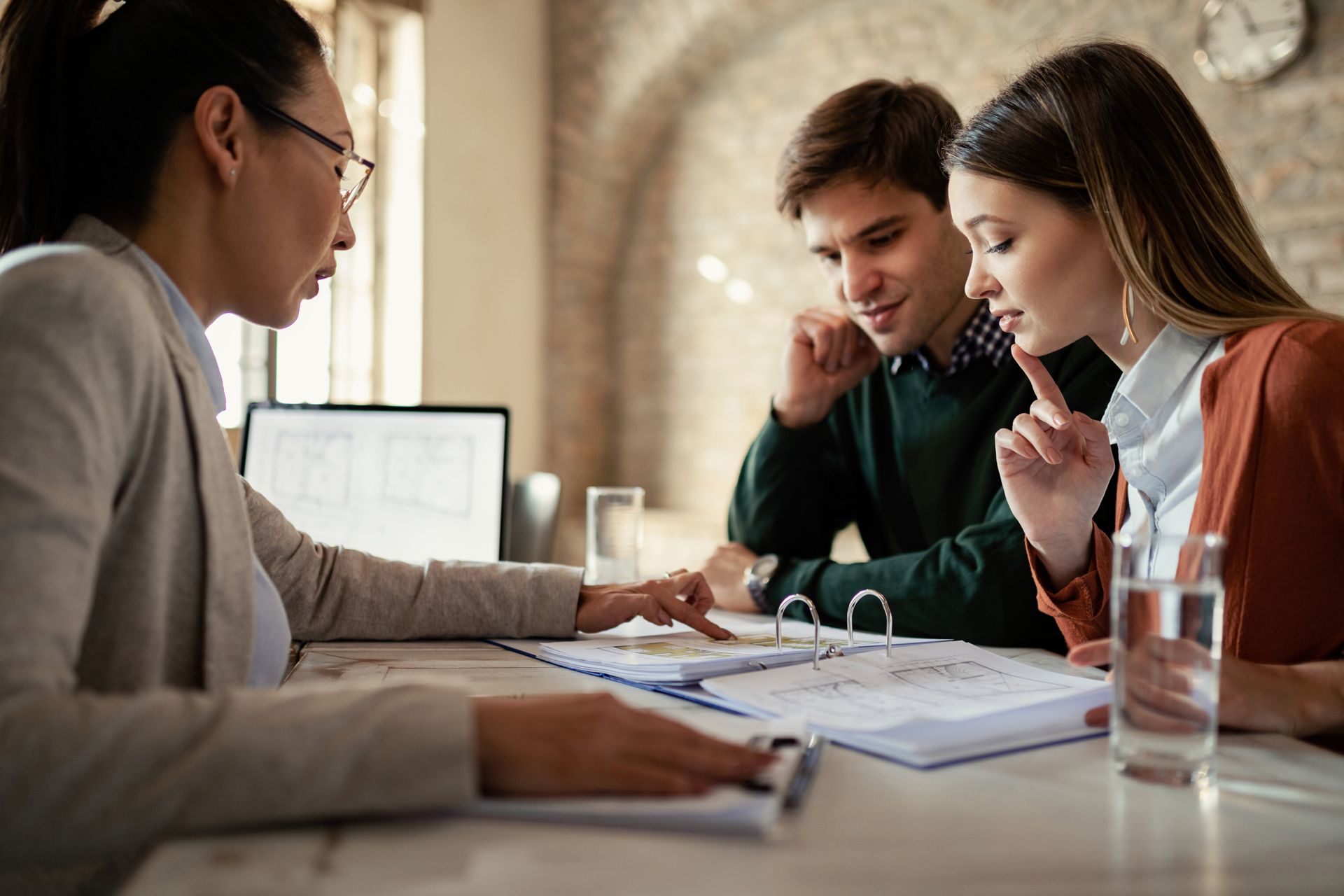 A man and a woman are sitting at a table talking to a woman.