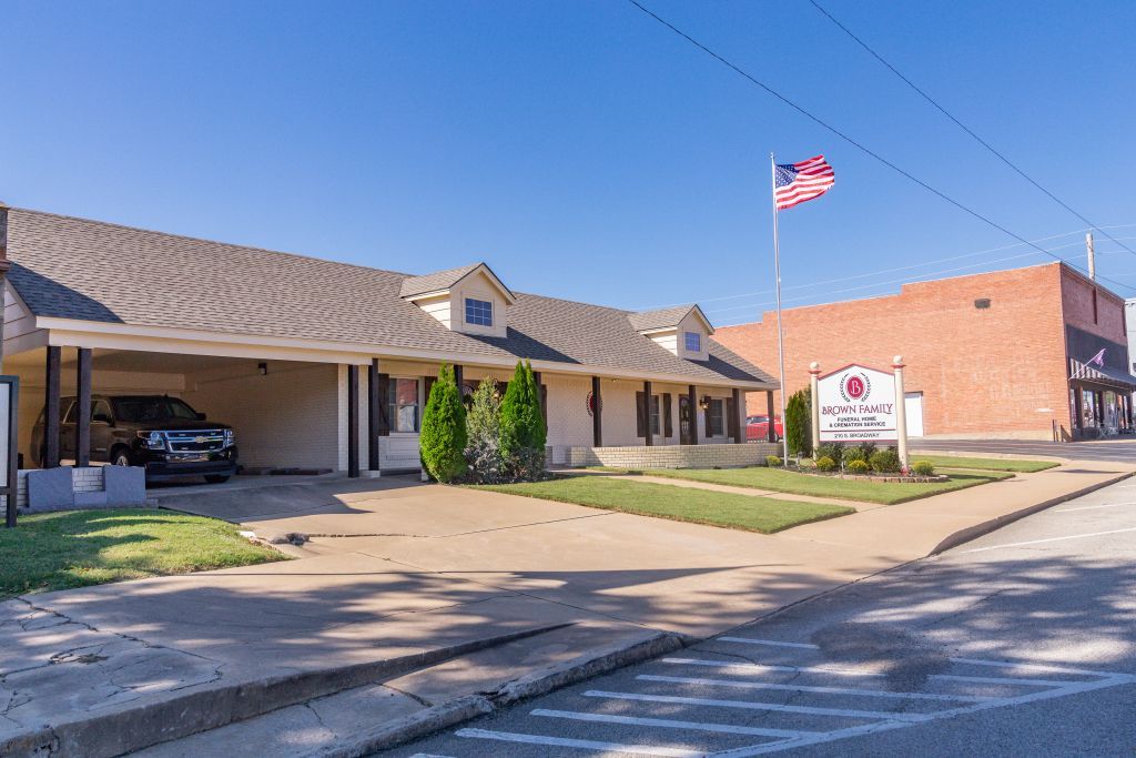 A funeral home with an american flag flying in front of it.