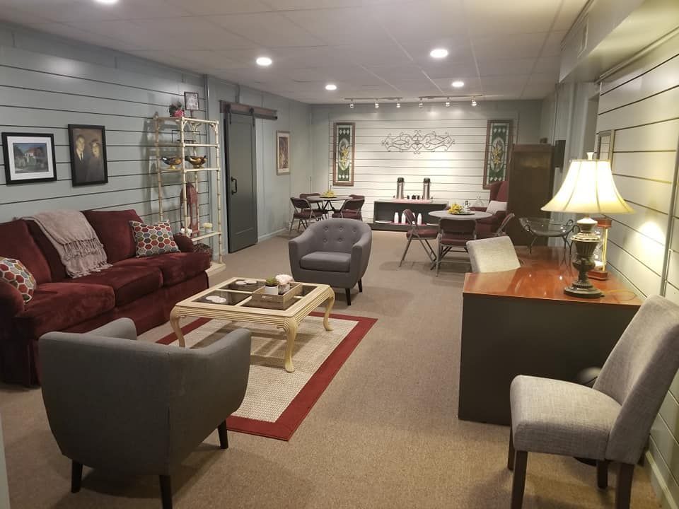 A living room with a couch , chairs , coffee table and desk.