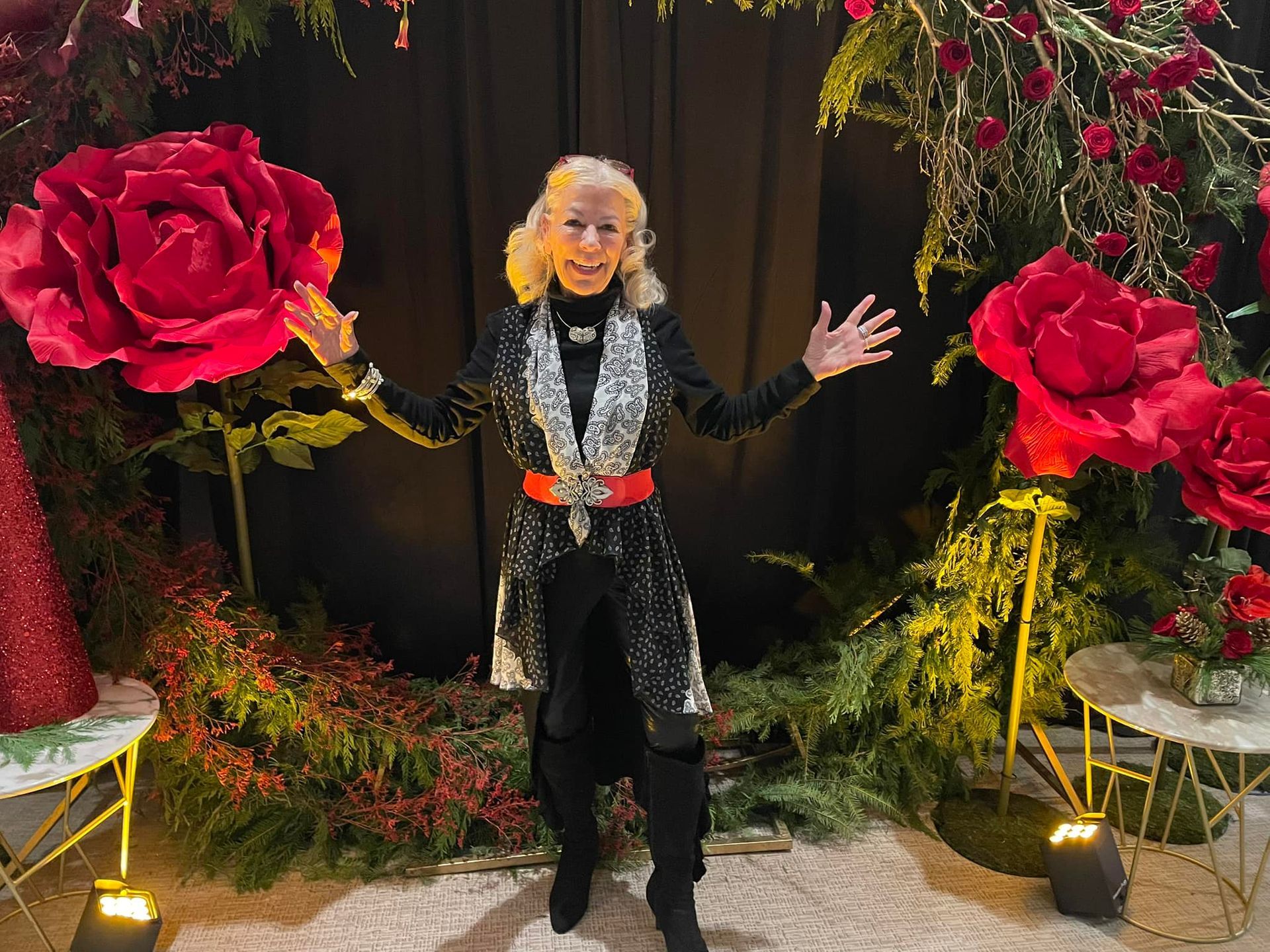 A woman is standing in front of a large red rose.
