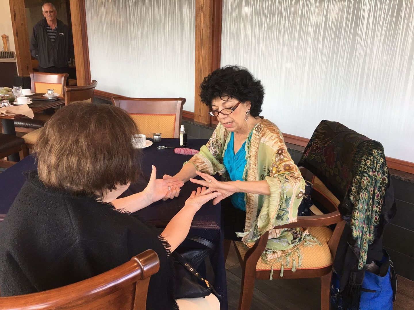 A woman is sitting at a table talking to another woman.