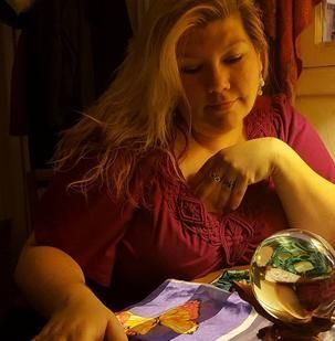 A woman is sitting at a table looking at a crystal ball.