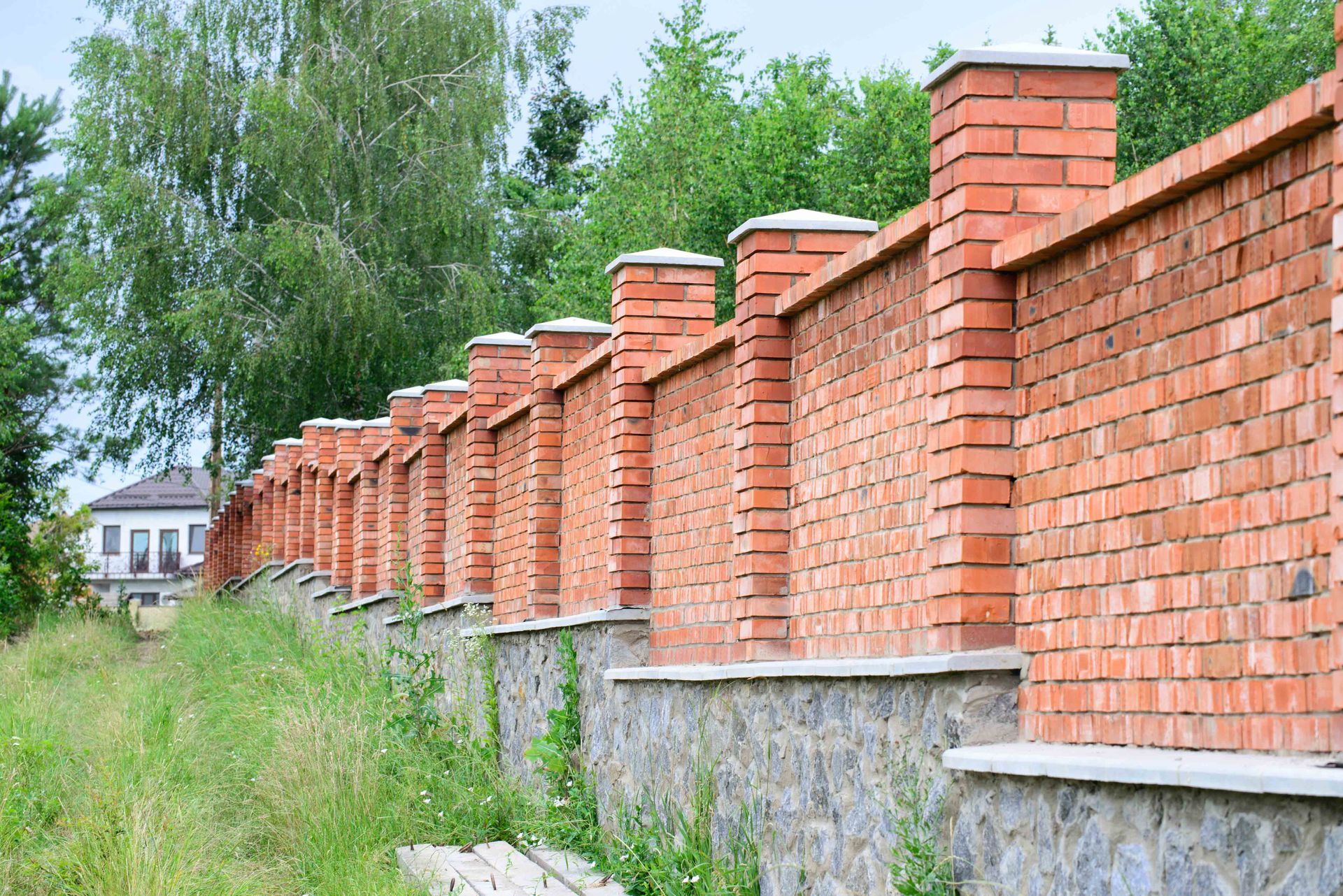 View of a high red brick fence in a residential setting.
