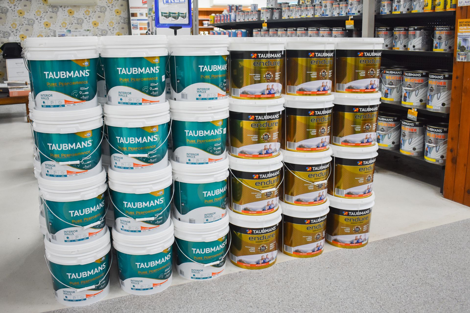 Paint cans of various bright colors with a paintbrush resting on top.