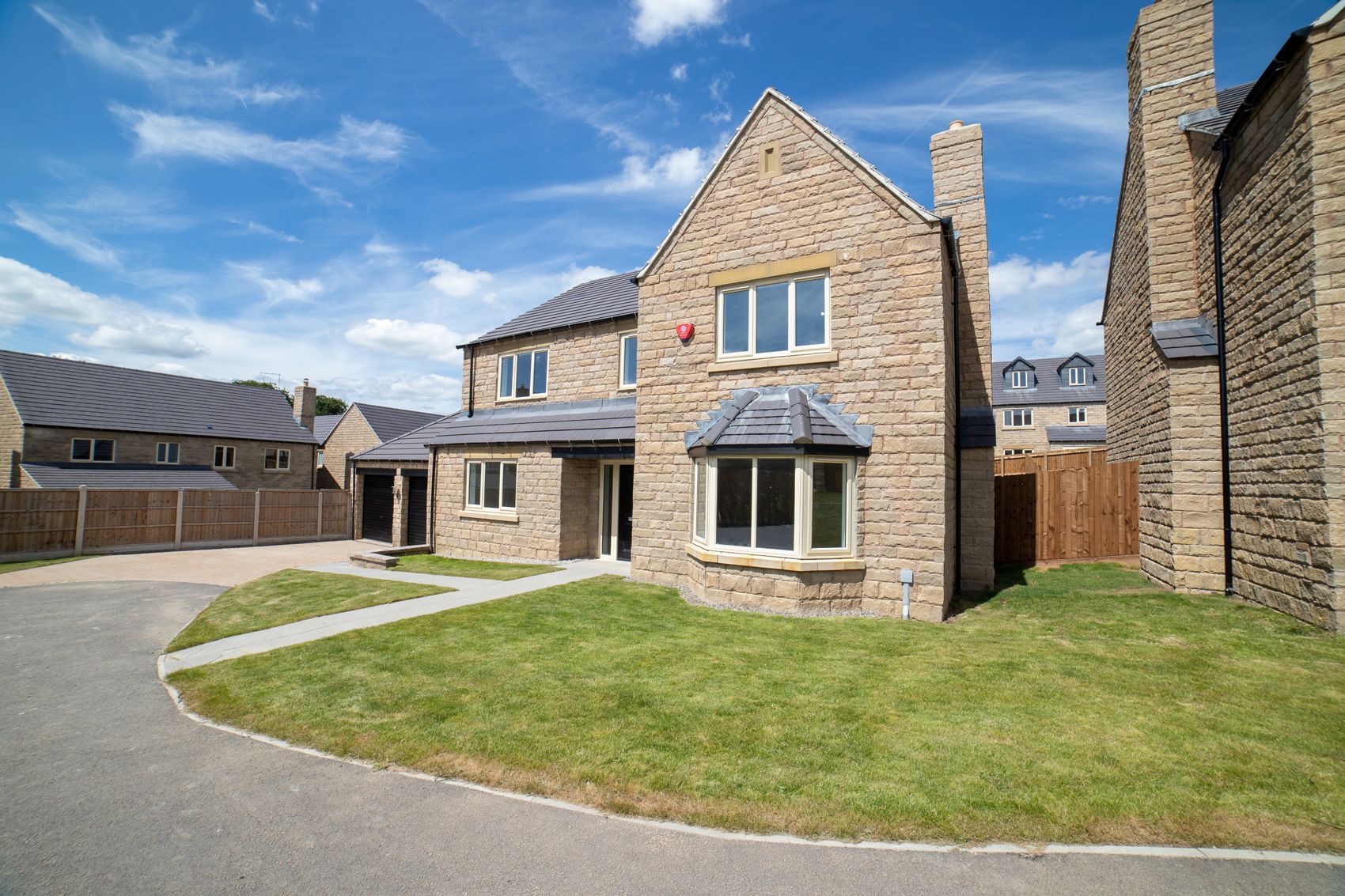 A large brick house with a large lawn in front of it in a residential area.