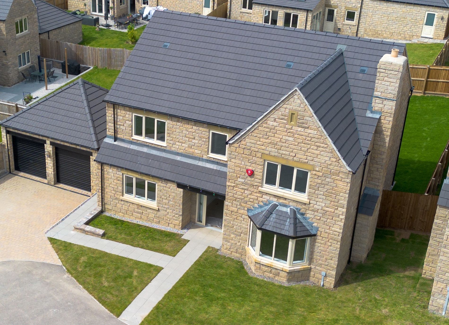 An aerial view of a large brick house with a gray roof