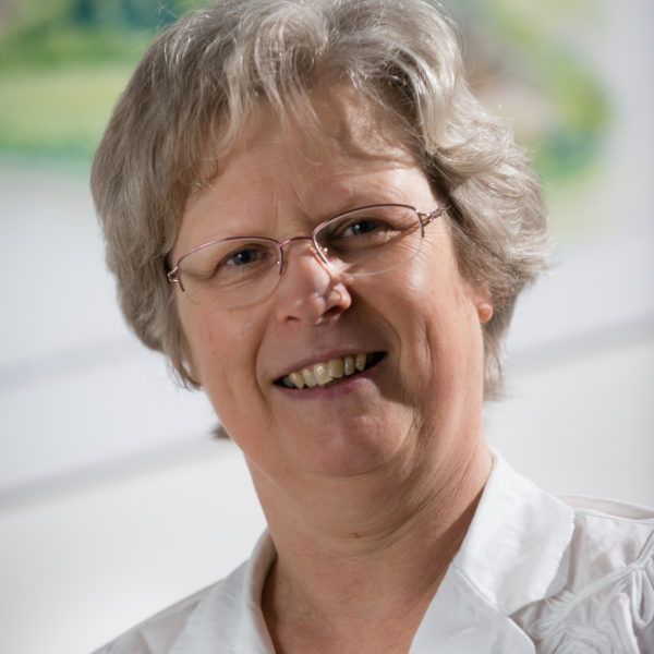 A woman wearing glasses and a white shirt is smiling for the camera.