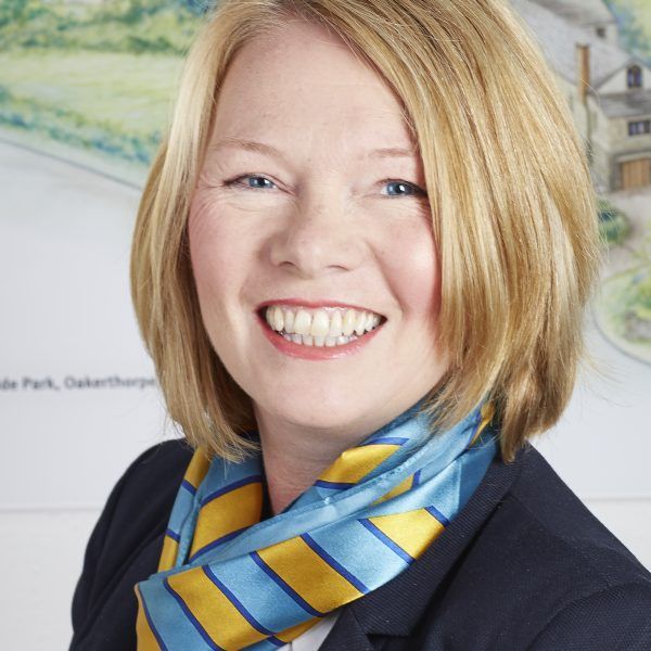 A woman wearing a blue and yellow scarf smiles for the camera
