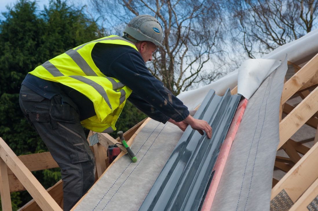 A man wearing a hard hat is working on a brick wall