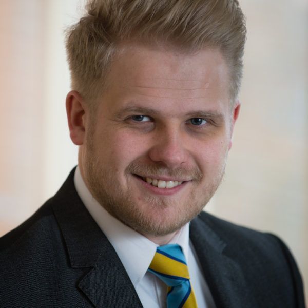 A man in a suit and tie is smiling for the camera
