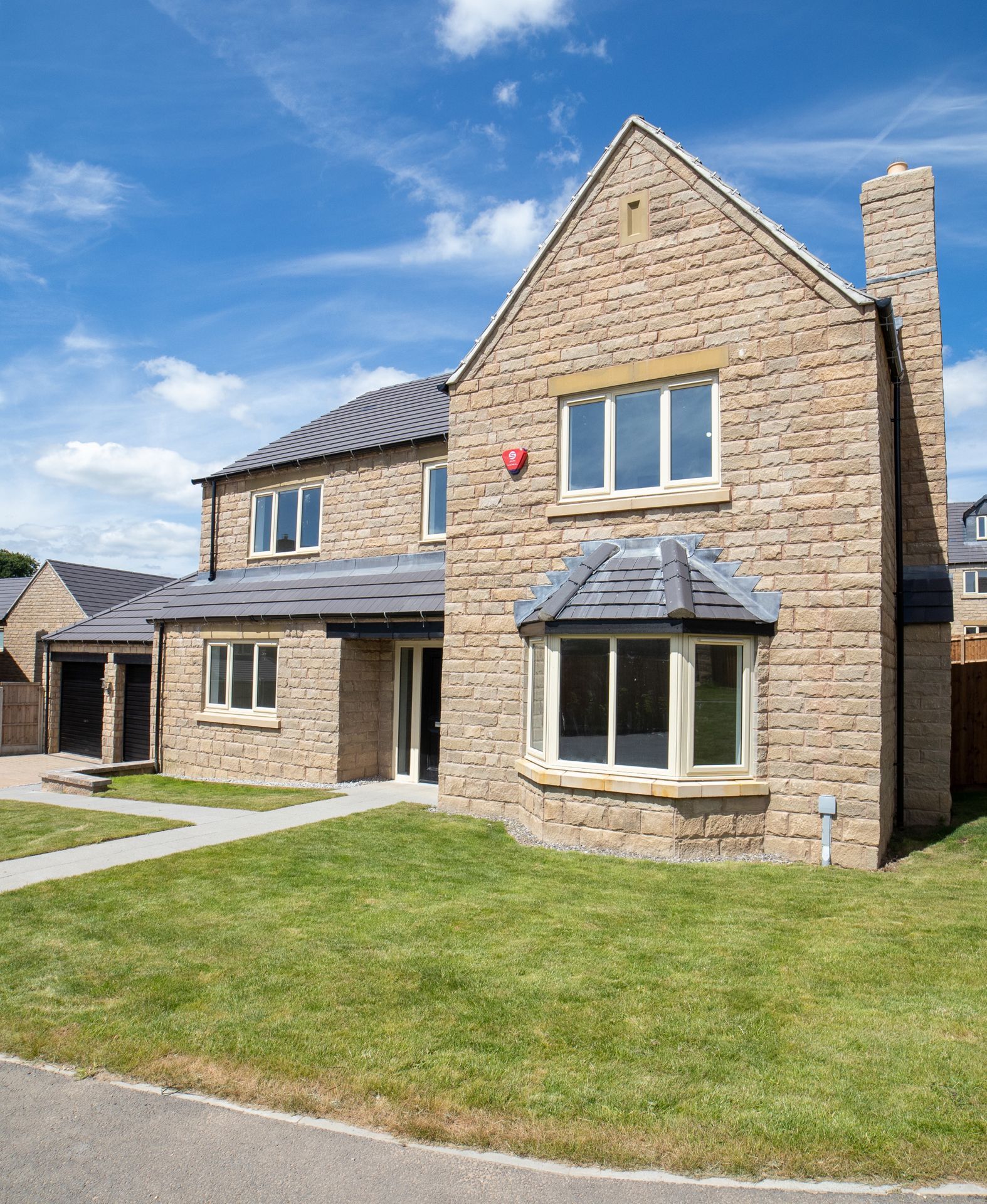 A large brick house with a red alarm on the side of it