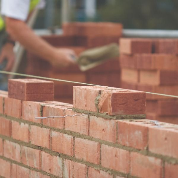 A brick wall is being built by a construction worker