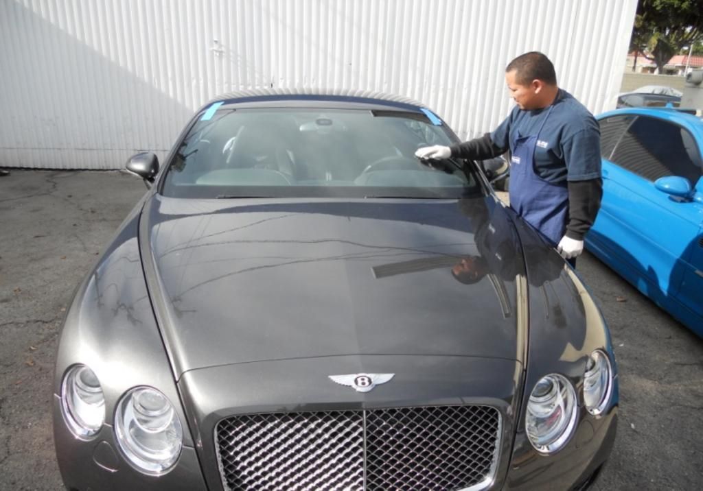 A man is working on the windshield of a bentley