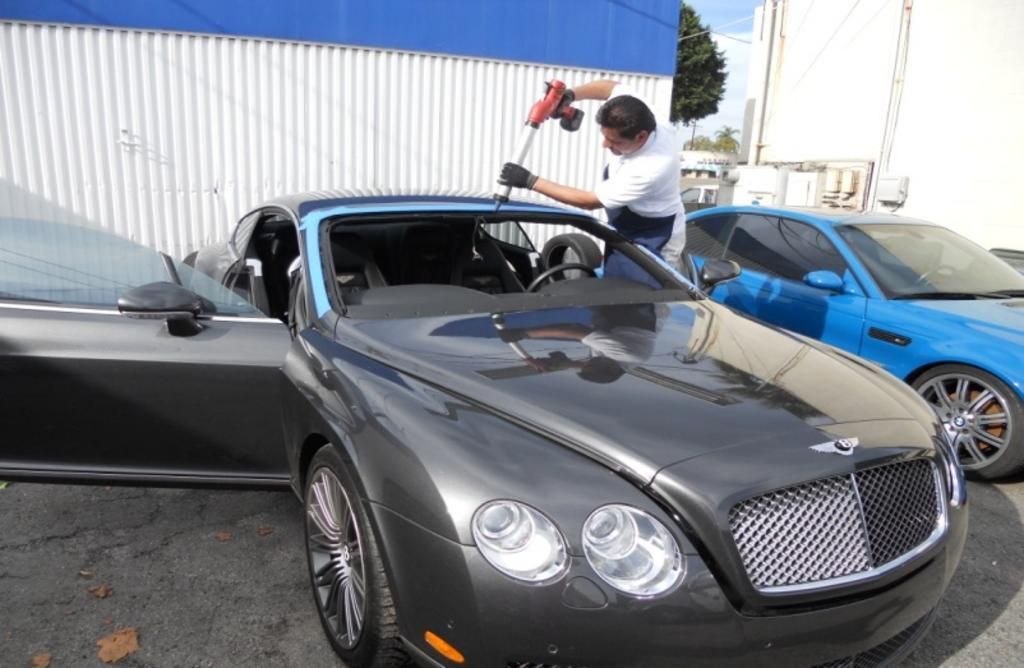 A man is installing a windshield on a bentley car