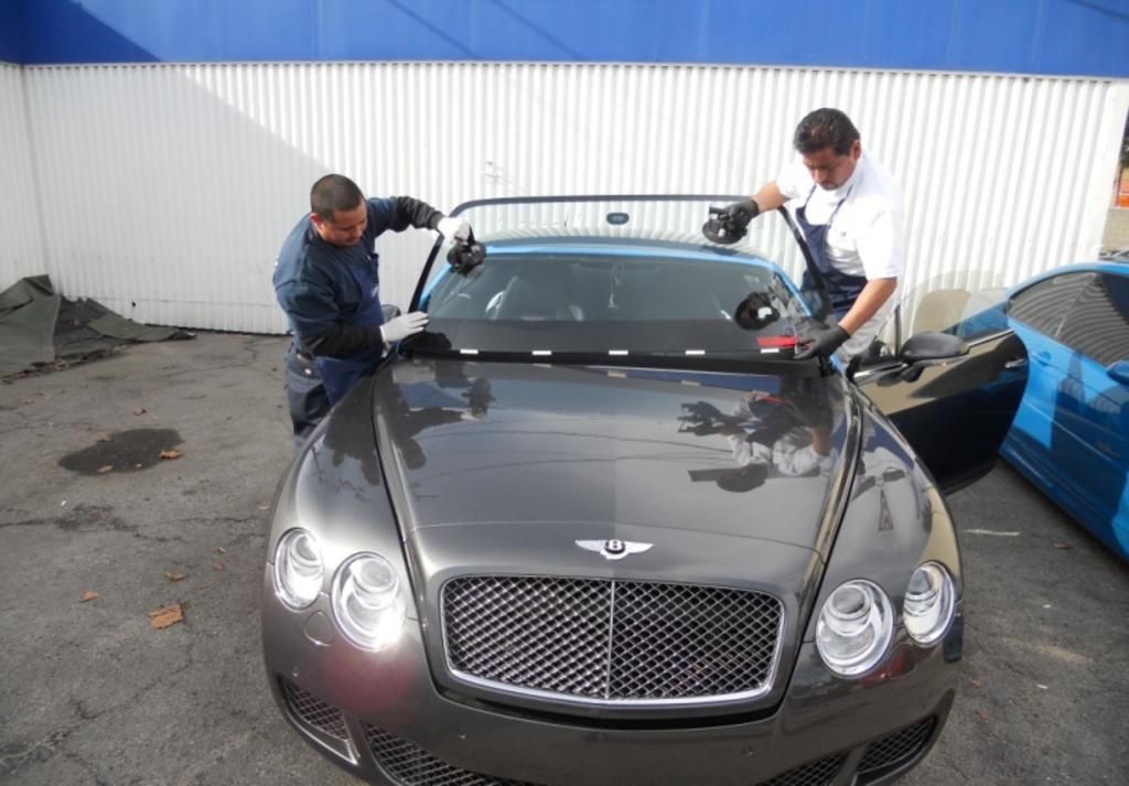 Two men are working on a bentley car