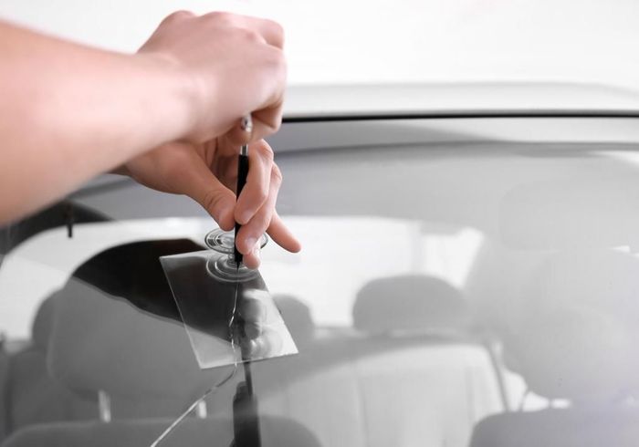 A person is fixing a broken windshield on a car.