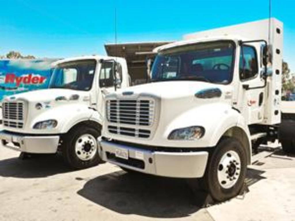 Two white trucks are parked next to each other in a parking lot.