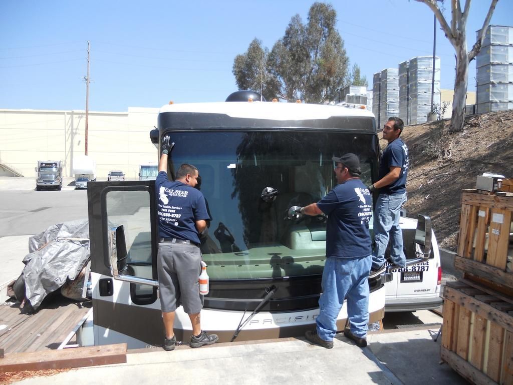 A group of men are working on a truck 's windshield