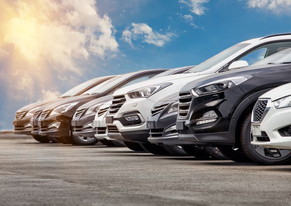 A row of cars are parked in a parking lot.