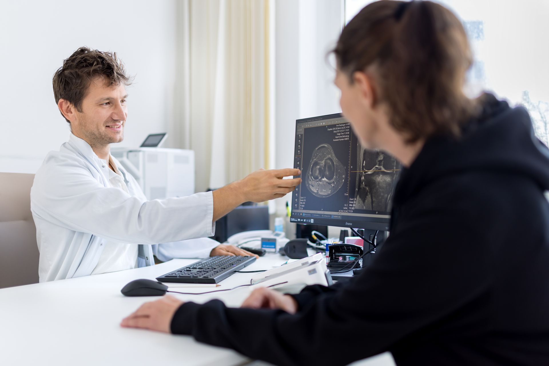 Ein Arzt spricht vor einem Computerbildschirm mit einem Patienten.