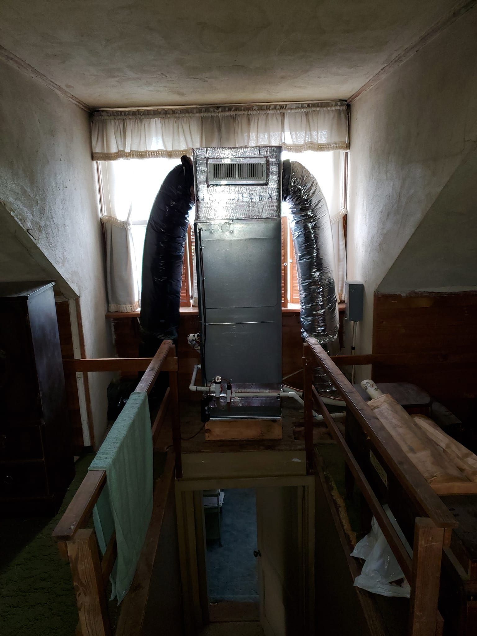 A very long pipe is coming out of the ceiling of a room.