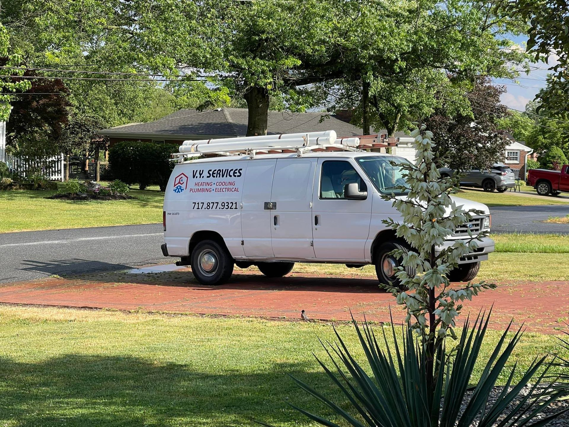 A white van is parked on the side of the road in front of a house.