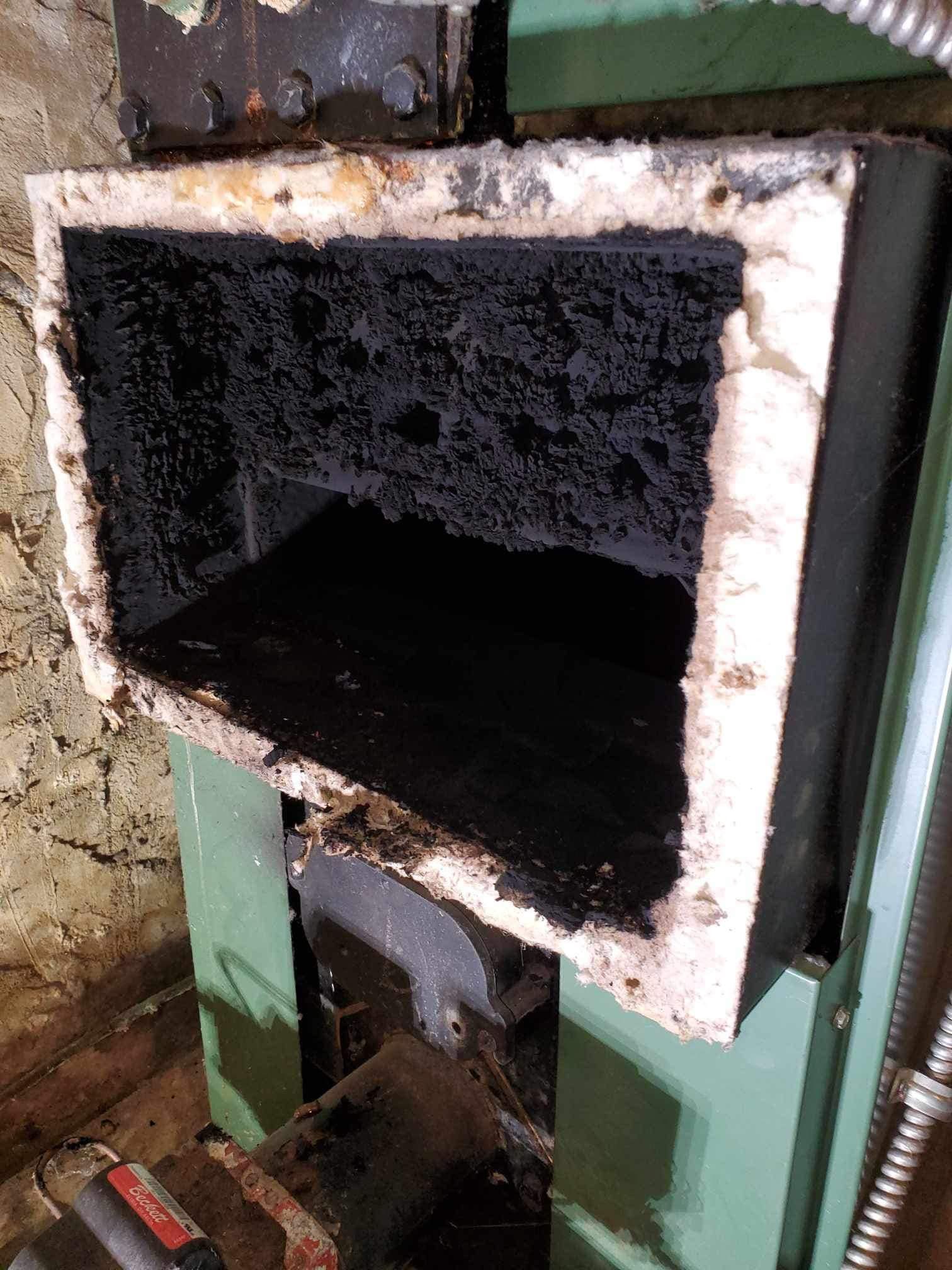 A close up of a dirty stove with a hose coming out of it.