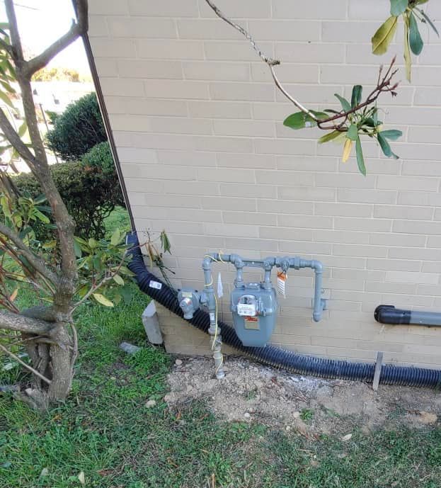 A gas meter is attached to the side of a brick building.