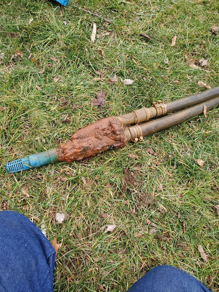 A person is sitting on the grass with a stick in the grass.