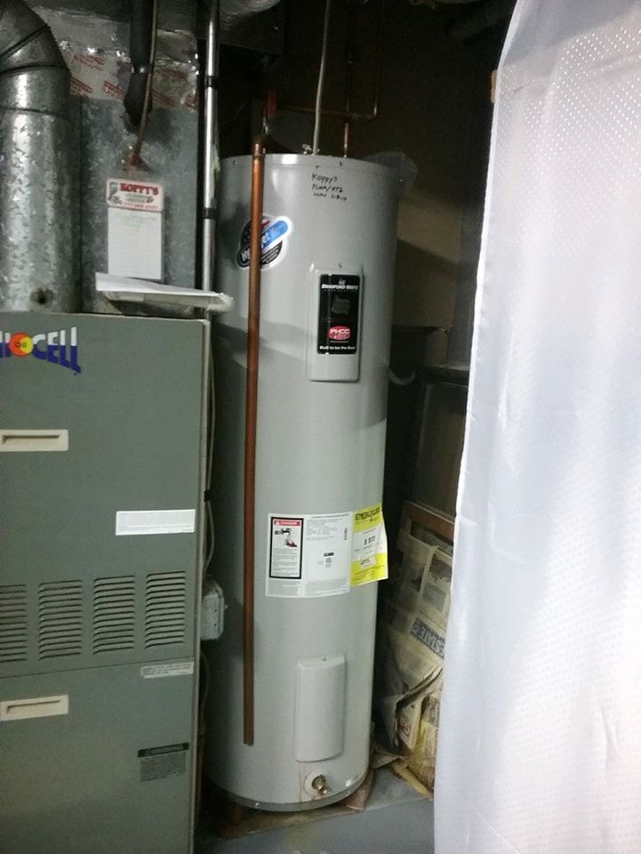 A water heater is sitting next to a furnace in a basement.