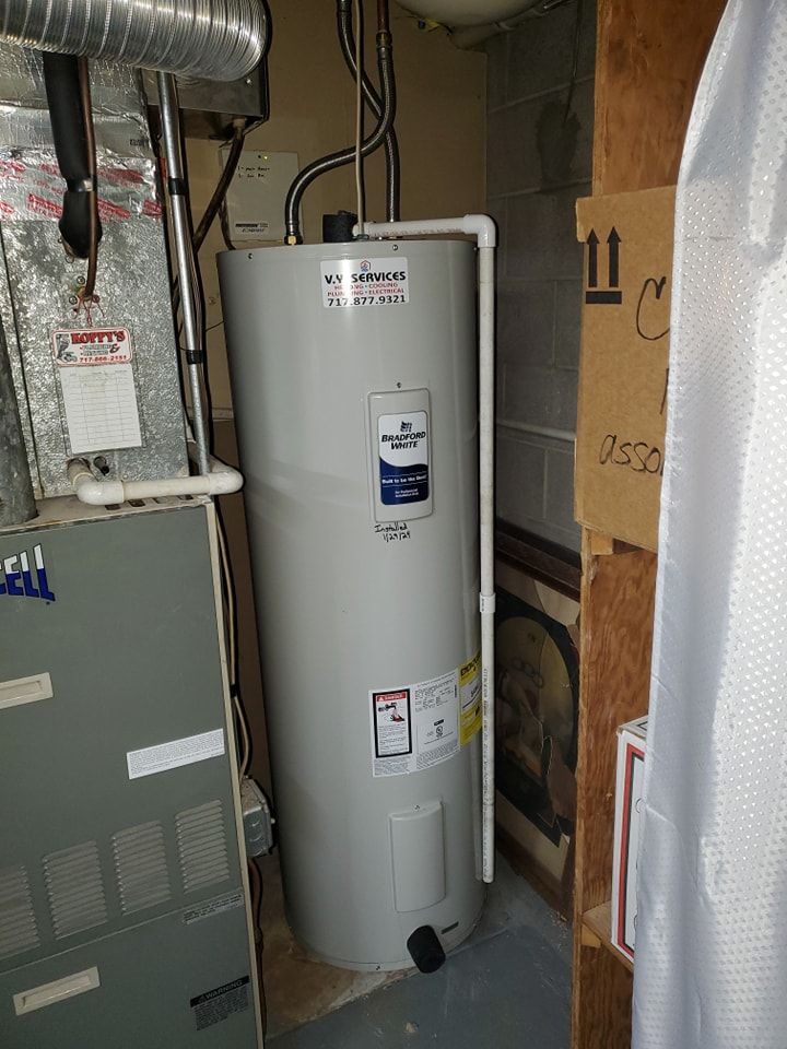 A water heater is sitting in a room next to a furnace.