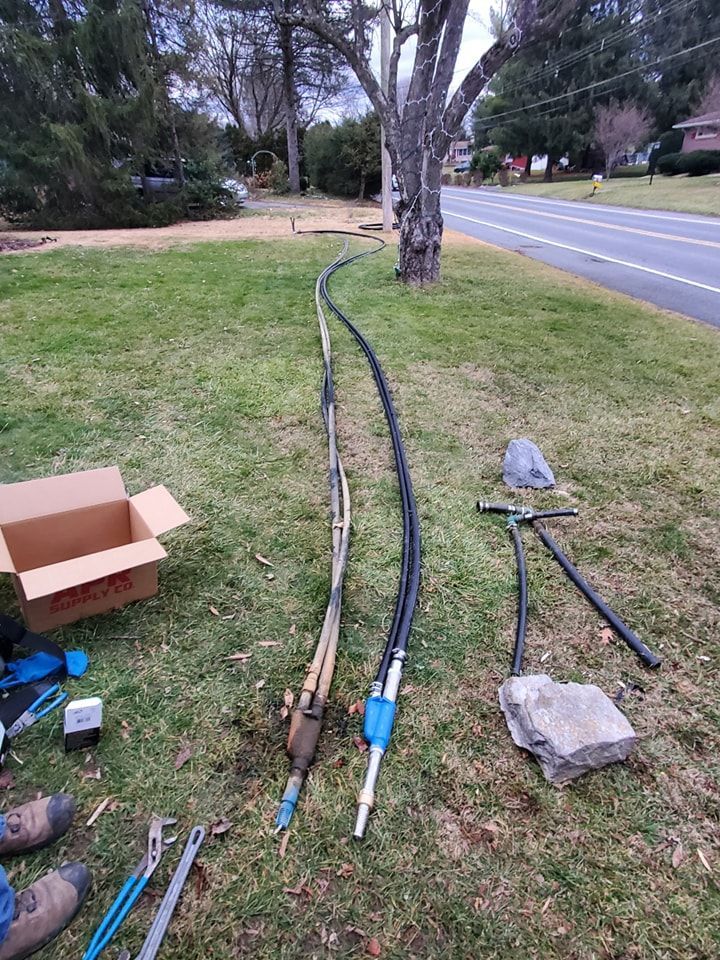A bunch of wires are laying on the grass next to a road.