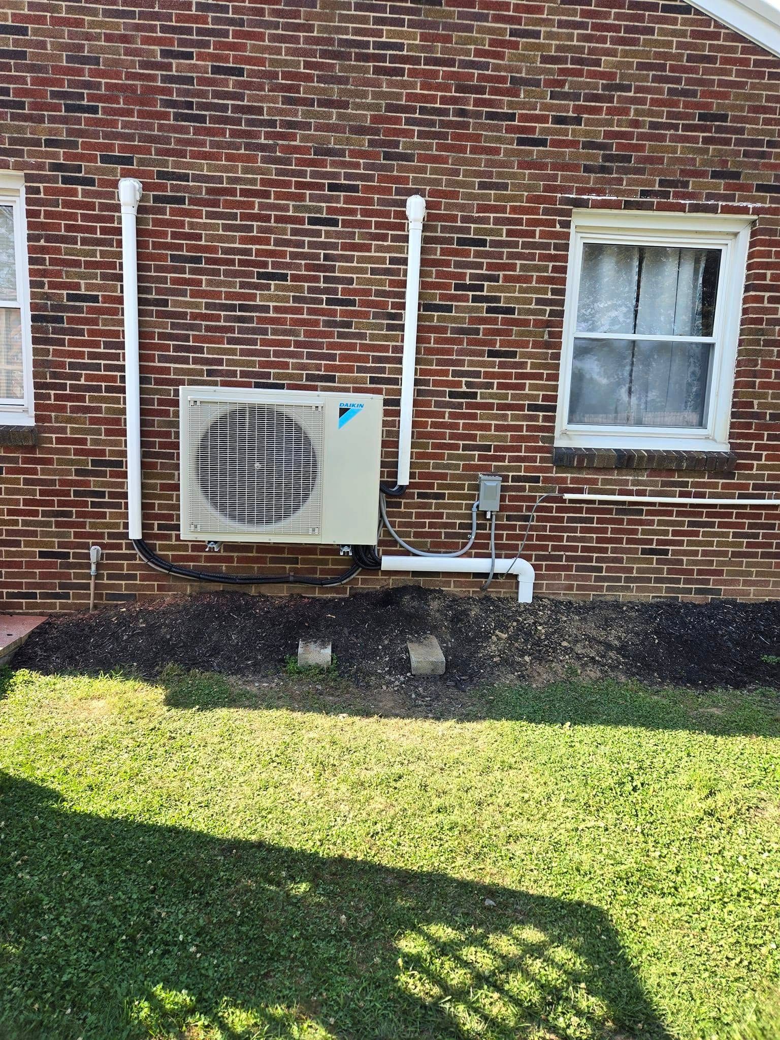 A brick house with a air conditioner on the side of it.