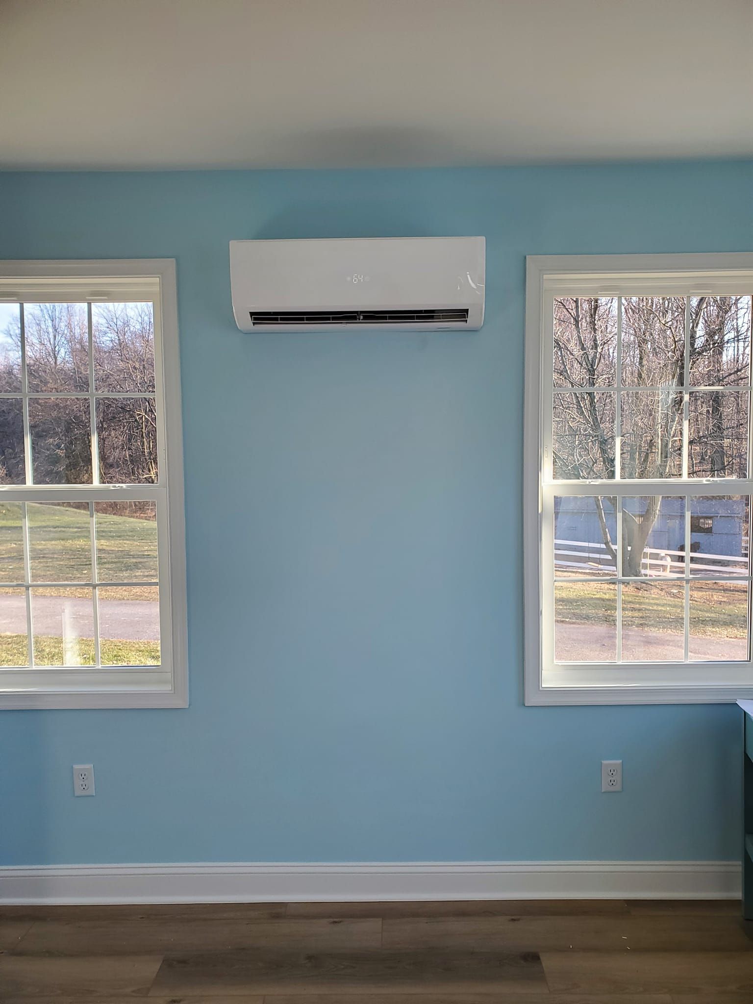 A room with two windows and a ceiling fan on the wall.