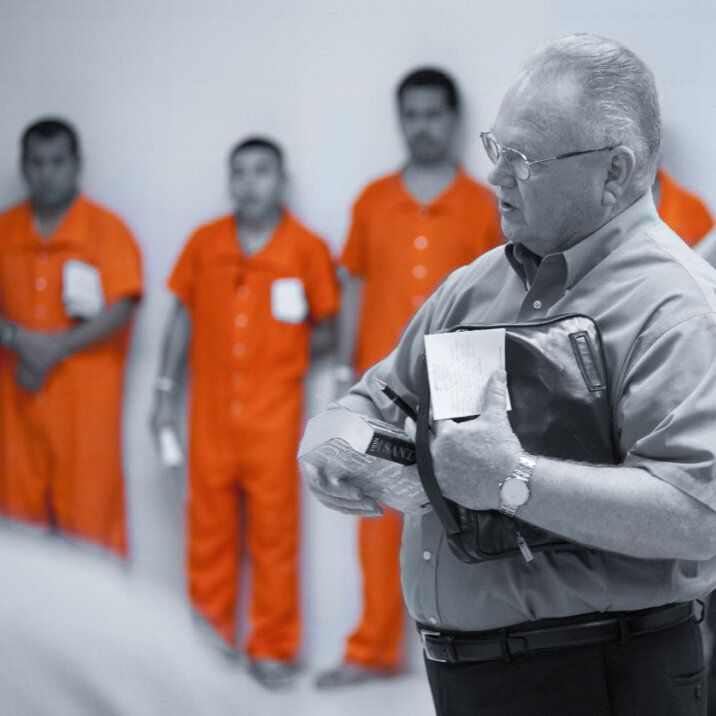 A man in an orange jumpsuit is holding a bible