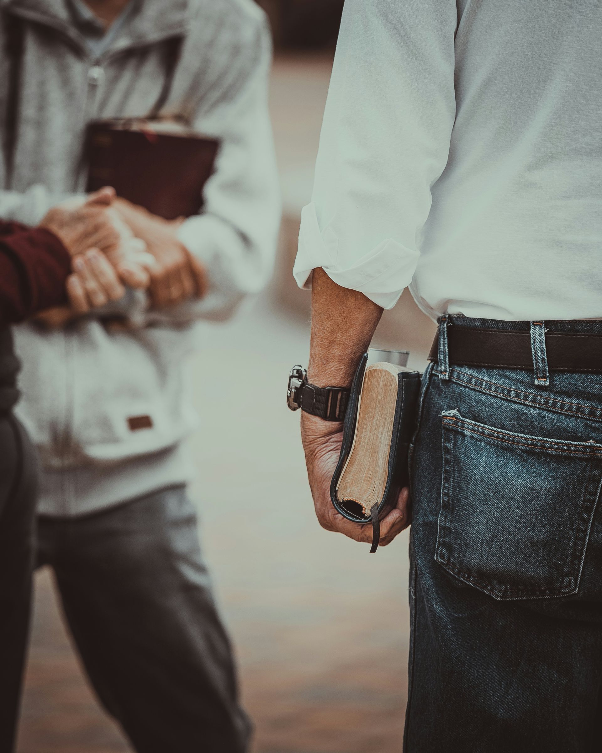 A man is holding a bible behind his back.