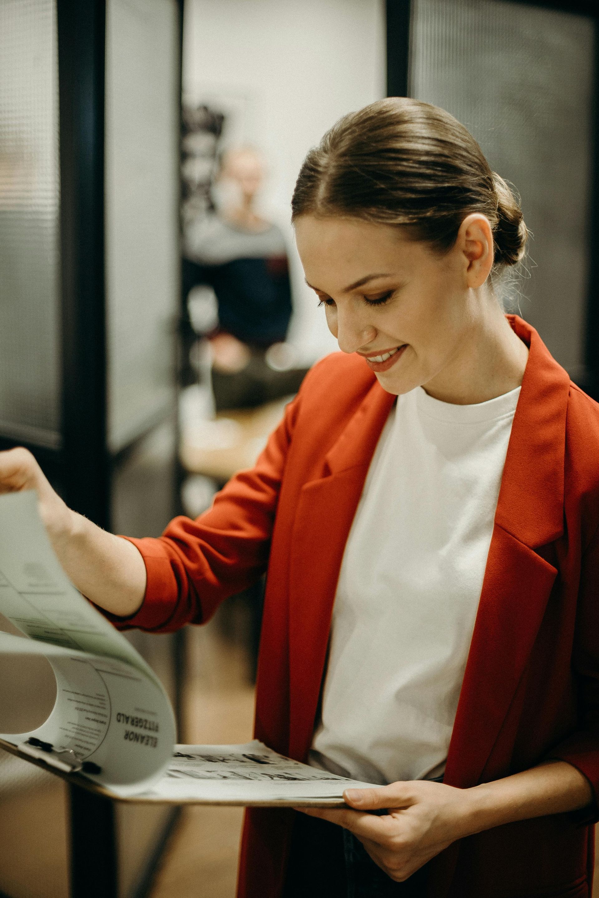 A woman in a red jacket is reading a book.