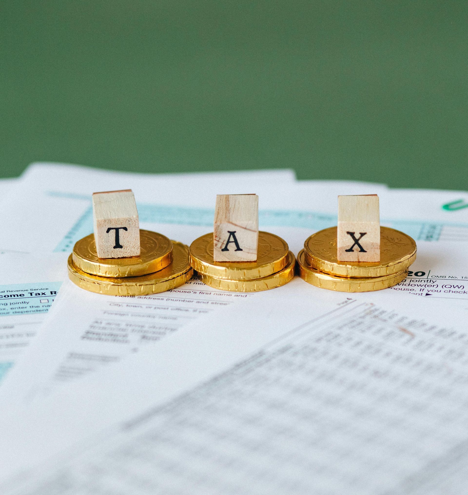 Three stacks of gold coins with wooden blocks that say tax