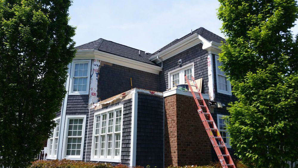 House with blue siding and white trim under renovation; ladder in front.
