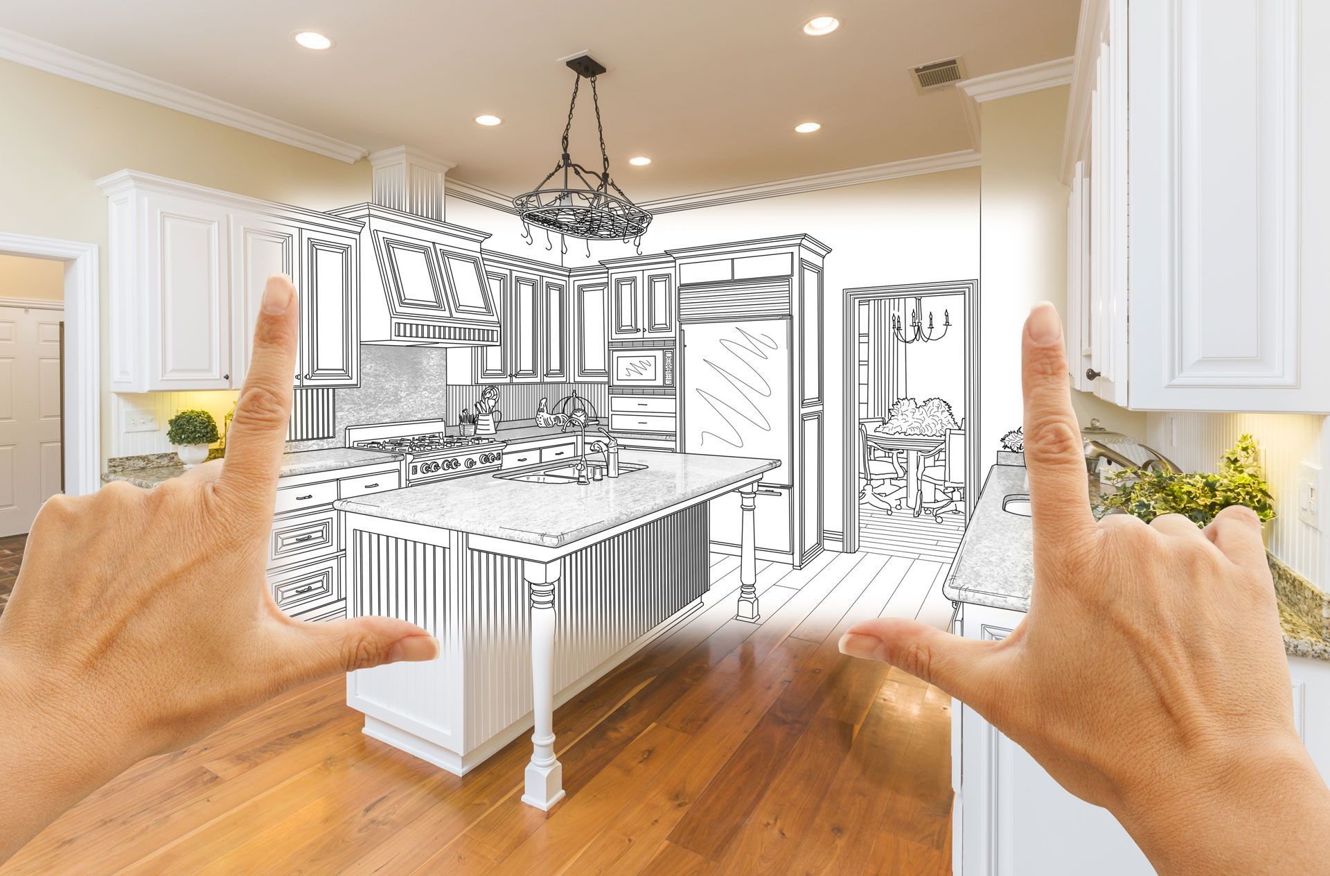 Hands framing a kitchen sketch overlaid on an existing kitchen with white cabinets and hardwood floors.