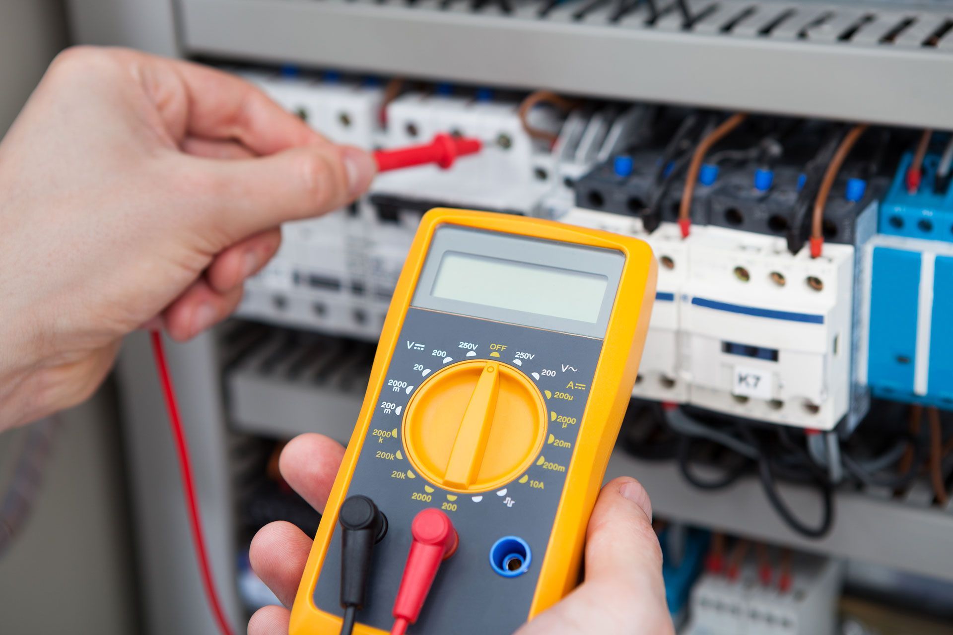 Electrician uses a multimeter to test wiring in a control panel.
