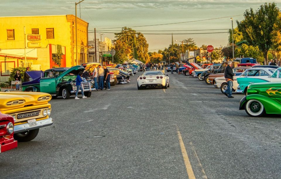 A row of cars are parked on the side of a street.