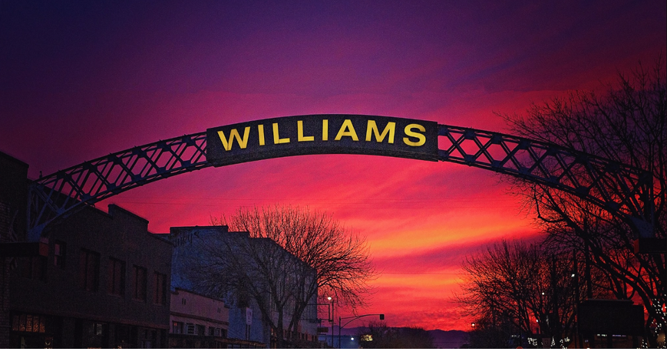 A bridge over a city street with a sunset in the background.