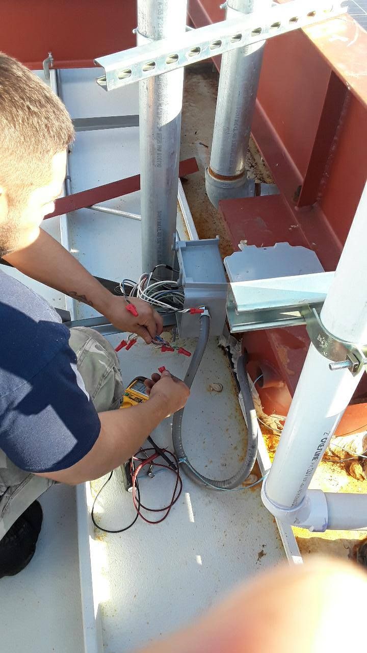 A man is working on a pipe with a screwdriver.