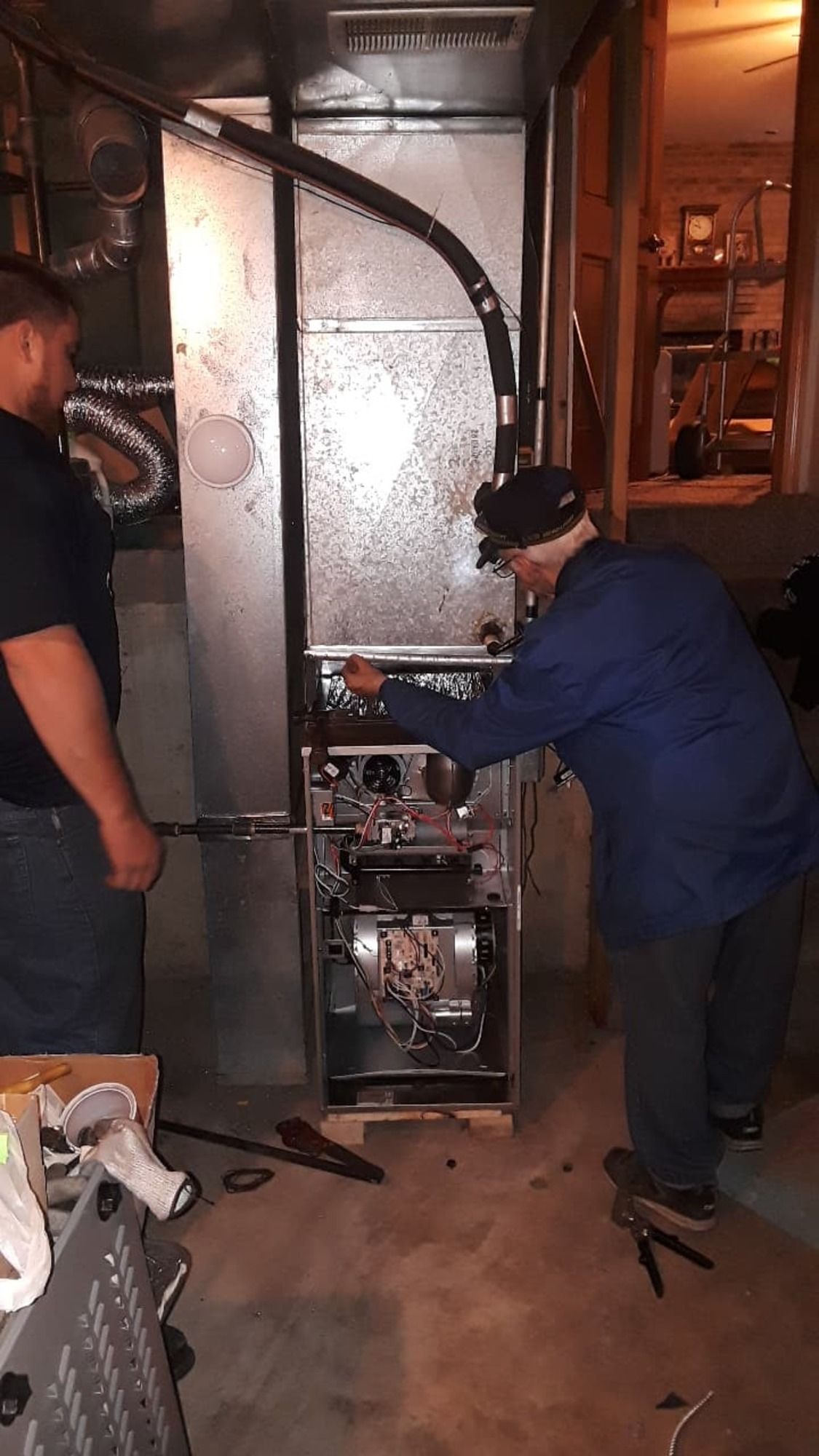 A man is working on a furnace in a basement.